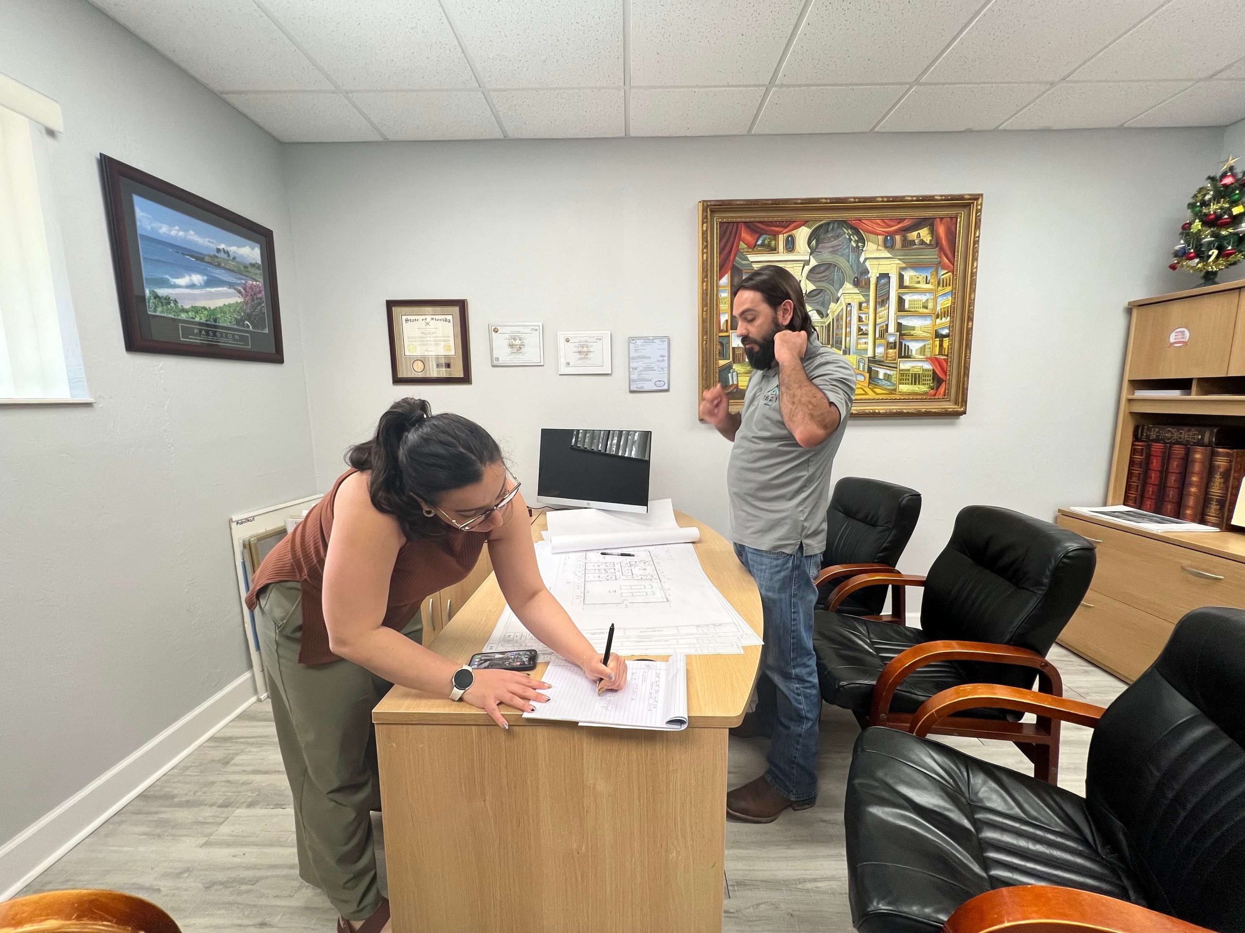 Neftali DeJesus, President/ General Contractor and Mary Vasilevsky, Vice President review floor plans for another Barndominium in Flagler County at Florida Green Building Construction's office.